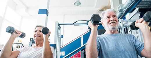 Image of senior woman and man lifting small weights at the gym